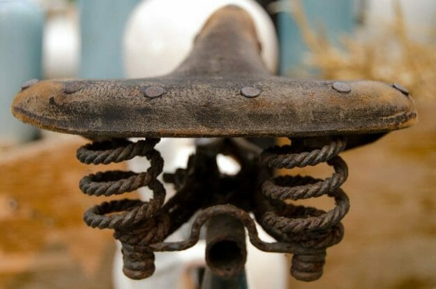 Rusted bike seat with worn leather cover