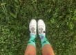 Legs of a woman wearing cycling shoes and colorful socks on grass