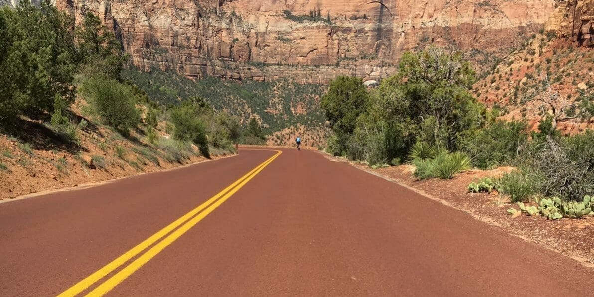 Down hill road in the mountains of Utah with a cyclist descending