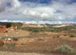 Narrow road in the middle of desert with mountains and big clouds